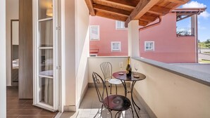 Un balcon avec une table et des chaises, une bouteille de champagne et une vue sur un bâtiment rose.