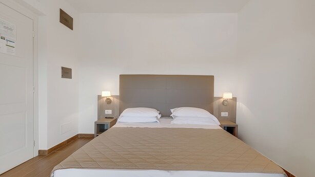 Ein Hotelzimmer mit einem großen Bett, zwei Nachttischen und Wandlampen.