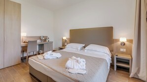 Une chambre d’hôtel comprenant un lit, des tables de chevet, un bureau et une armoire.