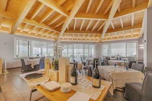 A restaurant with wooden beams on the ceiling, large windows, and tables set for dining. - Villa Carolina Golf View 13, Castelletto d’Orba, Italy (Castelletto d’Orba)