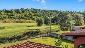 A golf course with a clear sky, surrounded by trees and a fence. - Villa Carolina Golf View 12, Castelletto d’Orba, Italy (Castelletto d’Orba)