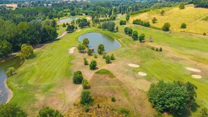 Un campo da golf con uno stagno, bunker di sabbia e un fiume.