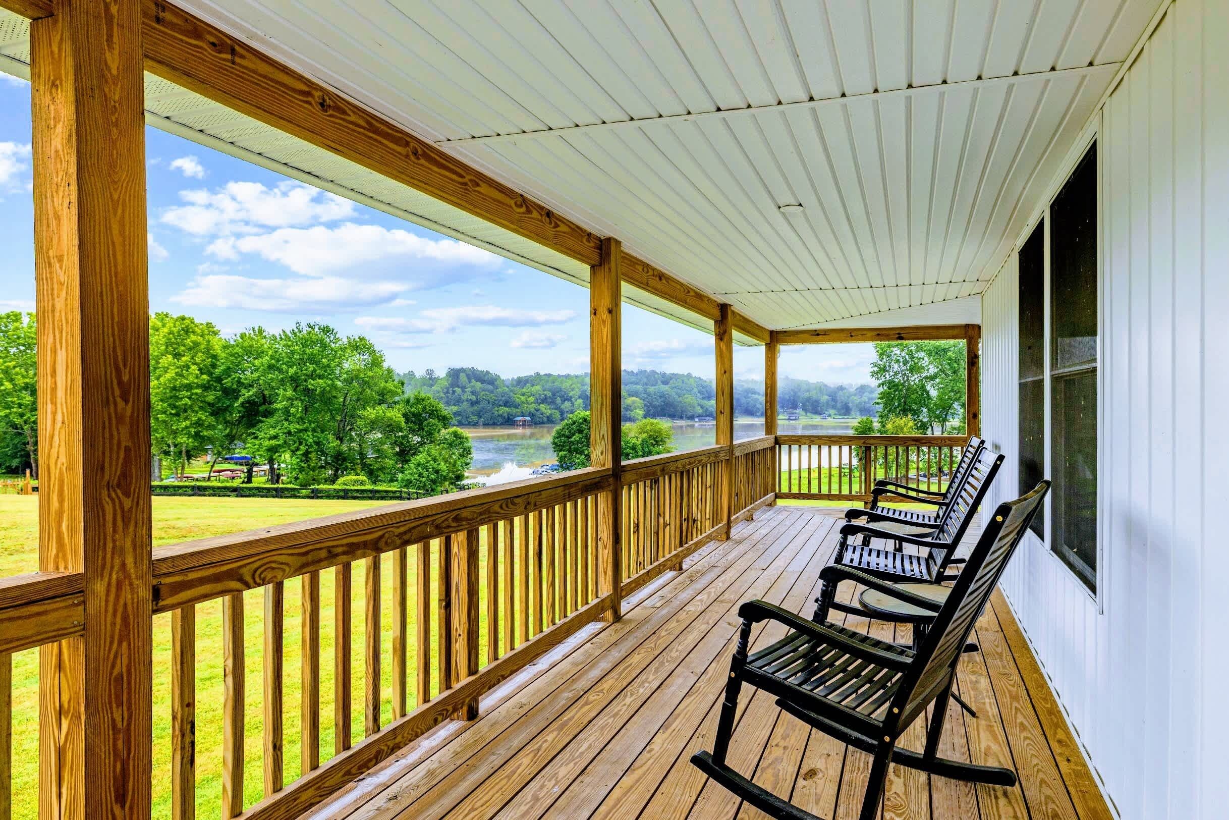 A wooden porch with a view of a lake and trees.