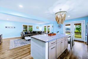 A spacious living area with a large island, a chandelier, and a view of the outdoors. - Lakefront Lake Anna | Hot Tub, Beach & Game Room (Orange)
