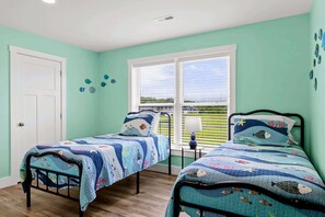 A bedroom with two beds, a window with blinds, a door, and wall decorations. - Lakefront Lake Anna | Hot Tub, Beach & Game Room (Orange)