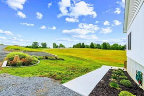 A residential property with a well-maintained lawn, a driveway leading to a house, and a clear sky. - Lakefront Lake Anna | Hot Tub, Beach & Game Room (Orange)