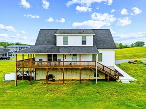 A two-story house with a covered porch, a small deck, and a front yard. - Lakefront Lake Anna | Hot Tub, Beach & Game Room (Orange)