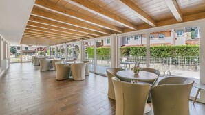 Un vaste espace intérieur avec des poutres en bois au plafond, de grandes fenêtres et un patio doté de meubles pour se détendre en plein air.