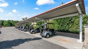 Un espace de stationnement couvert où sont alignées des voiturettes de golf.