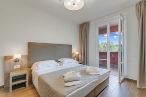 A hotel room with a bed, bedside lamps, a nightstand, a view of the outdoors through a sliding glass door, and a ceiling light.