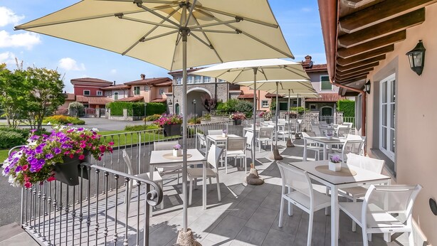 An outdoor patio area with multiple tables and chairs, large umbrellas, and potted plants. - Villa Carolina Golf View 5, Castelletto d’Orba, Italy (Castelletto d’Orba)