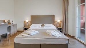 A hotel room with a large bed, two bedside tables with lamps, a desk with a chair, and a window with curtains. - Villa Carolina Golf View 5, Castelletto d’Orba, Italy (Castelletto d’Orba)