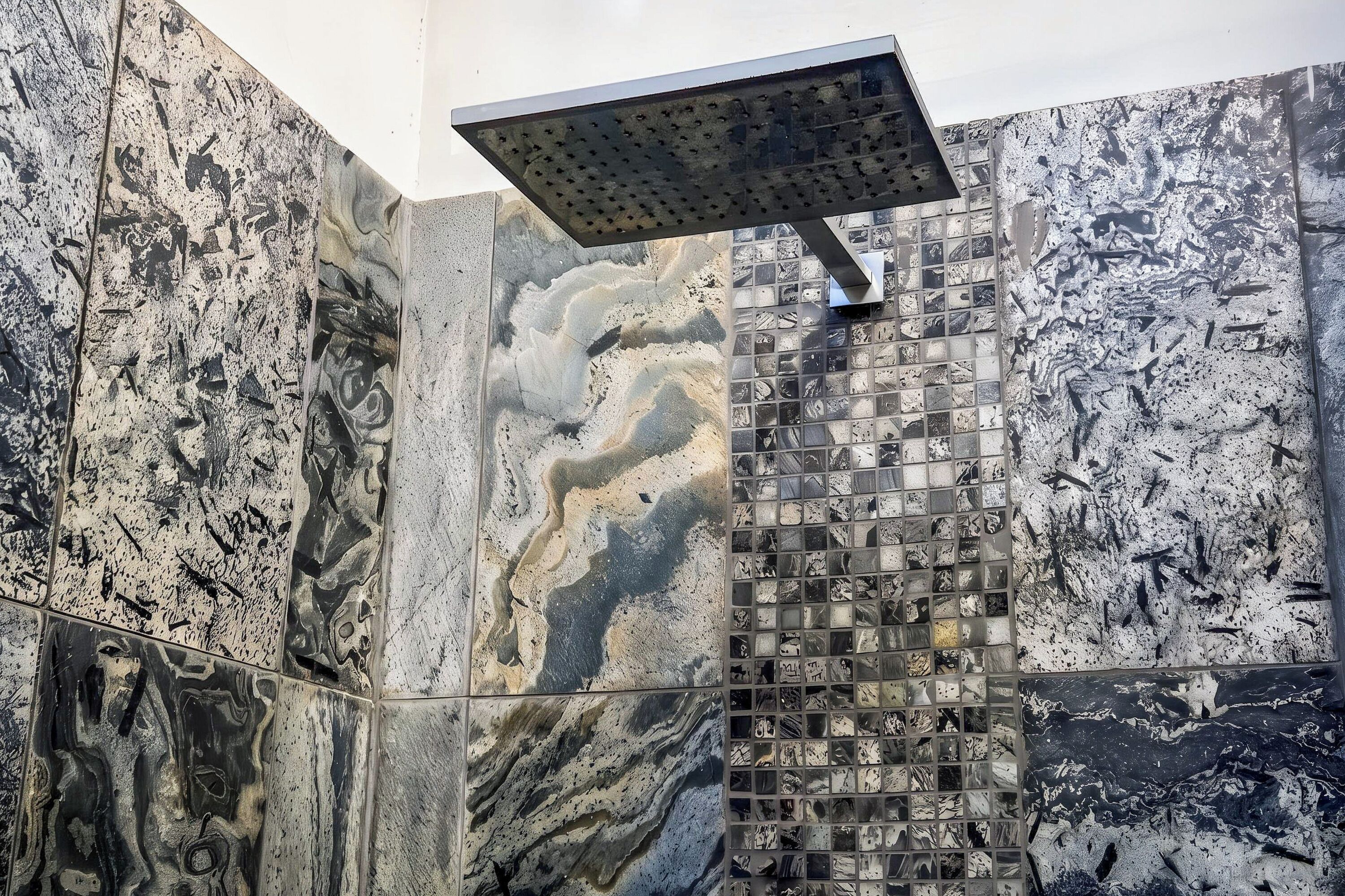 Une douche dotée d’un pommeau de douche à effet pluie et d’un mur au motif évoquant le marbre.