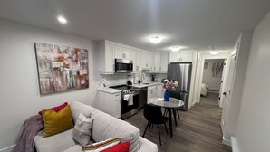 A modern apartment with a living room, kitchenette, and dining area. - Serenity Suite (Regina)