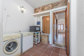 Ein Waschraum mit Waschmaschine, Trockner und einem kleinen Fernseher auf einem Regal.
