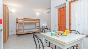 Ein Zimmer mit einem Etagenbett, einem Esstisch mit Stühlen und einer Tür.