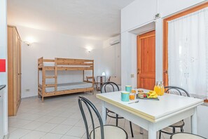 Ein Zimmer mit einem Etagenbett, einem Esstisch mit Stühlen und einer Tür.