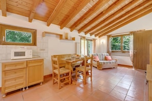 A cozy kitchen with wooden cabinets, a dining table, and a built-in microwave.