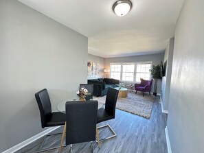 En moderne stue med spiseplads, store vinduer og udsigt over byen.