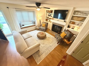 A living room with a sofa, armchairs, a TV, and a fireplace. - Southern charm awaits at Cobblestone Cottage (Wilmington)