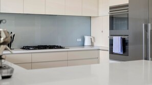 Une cuisine moderne équipée d’une cuisinière à gaz, d’une bouilloire et d’un four en acier inoxydable.