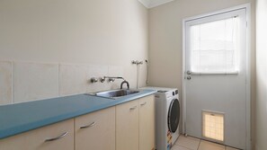 A compact kitchen with a sink, a washing machine, and a door with a window.