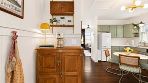 Una cucina con mobili in legno, una macchina da caffè, un tavolo da pranzo con sedie e una lampada a sospensione.