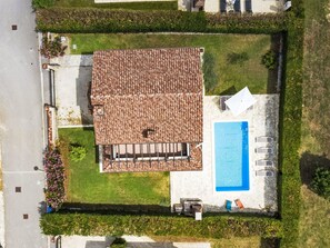 Vista aérea de una propiedad con techo de tejas, piscina y zona de patio.