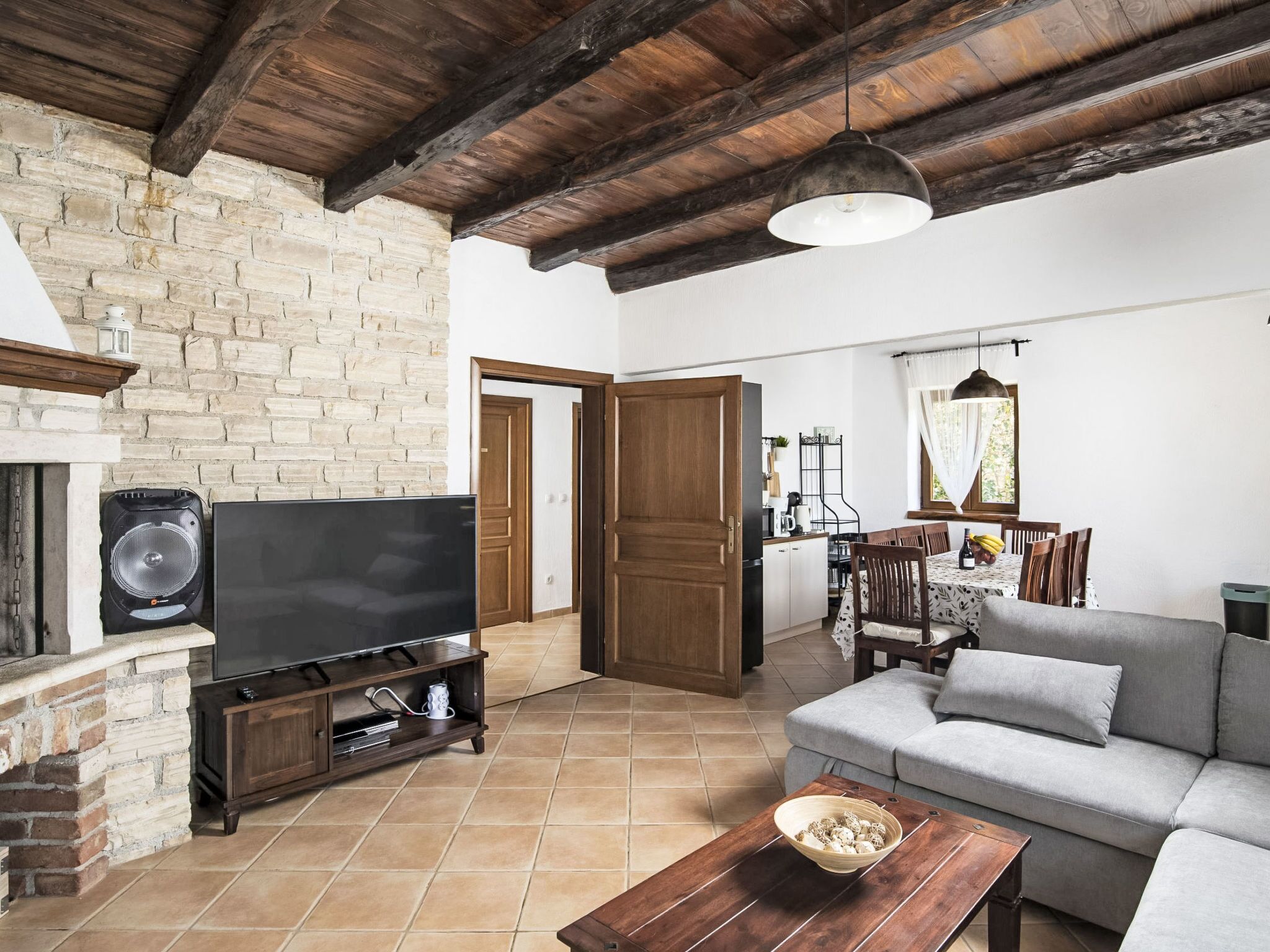 A living room with a stone fireplace, a flat-screen TV, a sofa, and a dining area with a table and chairs.