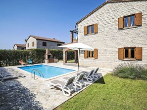 Una casa de pedra amb piscina, gandules i zona de barbacoa.