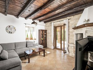 A living room with a sofa, a table, a clock, and a fireplace. - Vacation home Orlene by Interhome (Pula/Vodnjan)