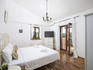 Un dormitorio con cama, televisión, lámpara en el techo y vistas al exterior.