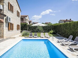 Una piscina con sillas de descanso y una sombrilla blanca.