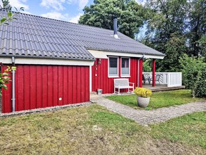 A red building with a grey roof, a white bench, and a potted plant. - Vacation home Carla by Interhome (Extertal)