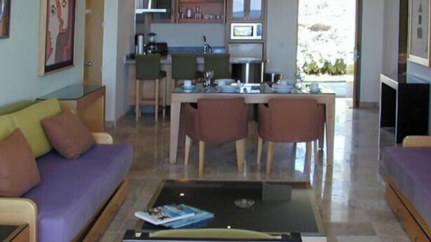 Uma sala de estar moderna com sofá, mesa de centro e área de jantar.
