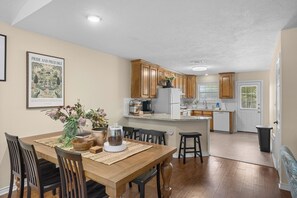 Una cocina moderna con armarios de madera, un comedor con una mesa de madera y una isla de cocina.