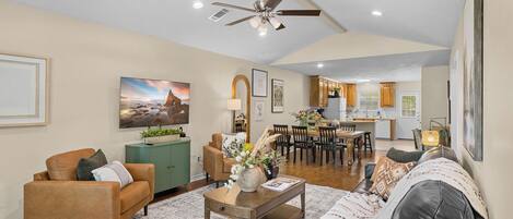 A spacious living area with a dining table, sofas, and a kitchen in the background.