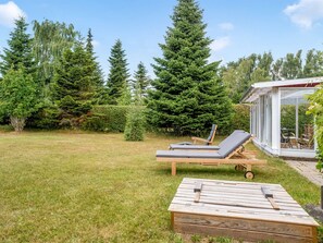 A backyard with a wooden deck, two lounge chairs, and a glass-enclosed patio area. - "Anina" - 300m from the sea by Interhome (Idestrup)