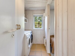 A laundry room with a washing machine, a drying rack, and a window with a view of greenery. - "Anina" - 300m from the sea by Interhome (Idestrup)
