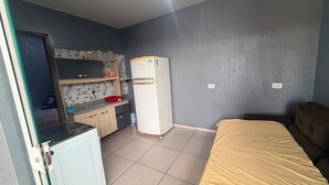 Quarto compacto com cozinha compacta, uma cama e um pequeno armário.