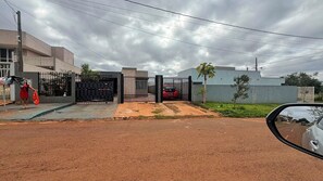 A residential area with a gated entrance, a parked car, and a person standing near the gate. - Studio apartment in Foz with Wi-Fi, garage, and security cameras. (Foz do Iguaçu)