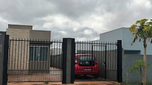 A gated property with a red vehicle parked inside. - Studio apartment in Foz with Wi-Fi, garage, and security cameras. (Foz do Iguaçu)