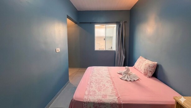 Quarto com cama, janela com cortinas e luminária no teto.