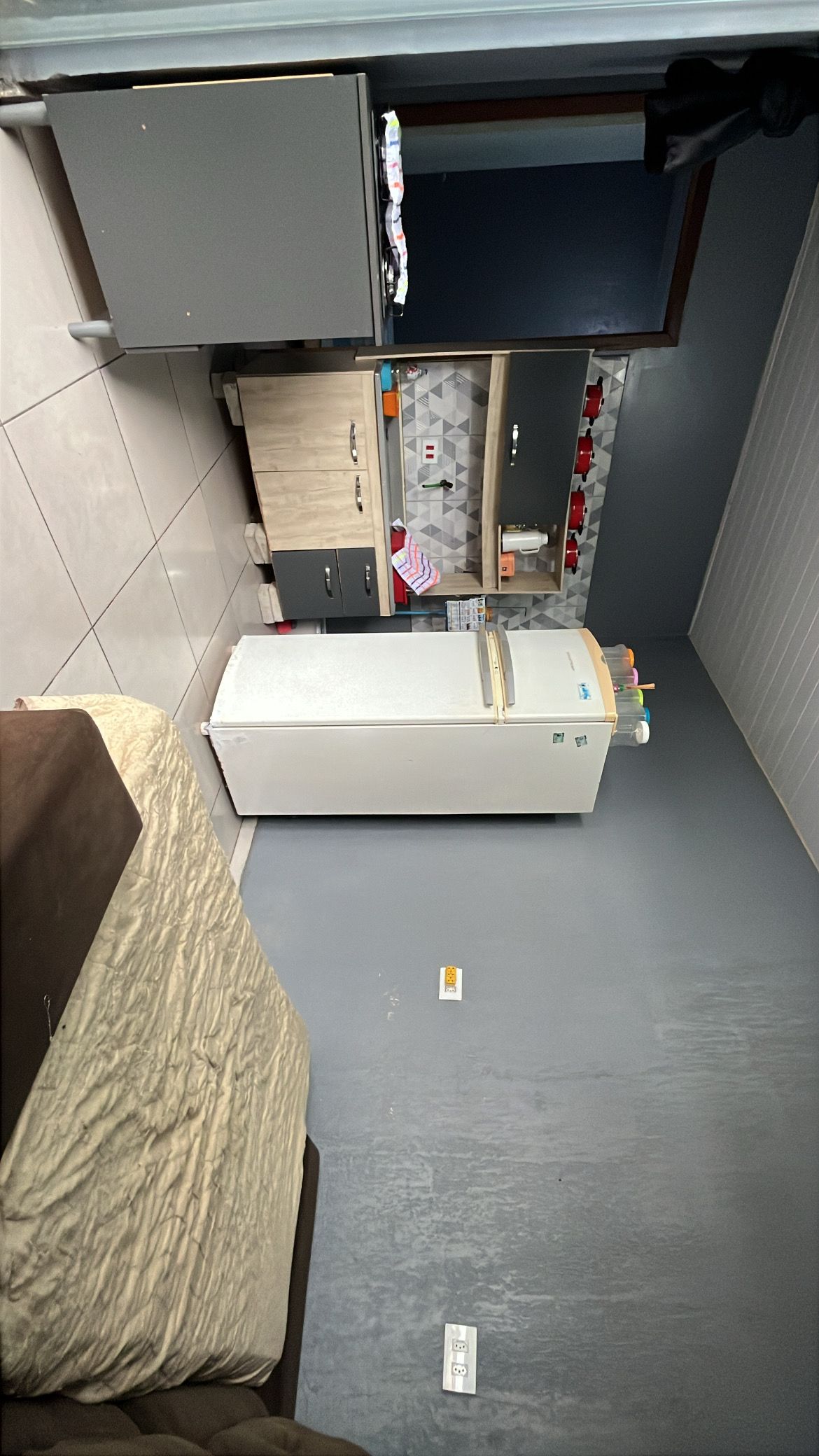 Ein gemütlicher Raum mit einem Bett, einem weißen Kühlschrank, einer kleinen Küchenzeile inklusive Mikrowelle und einem Fenster.