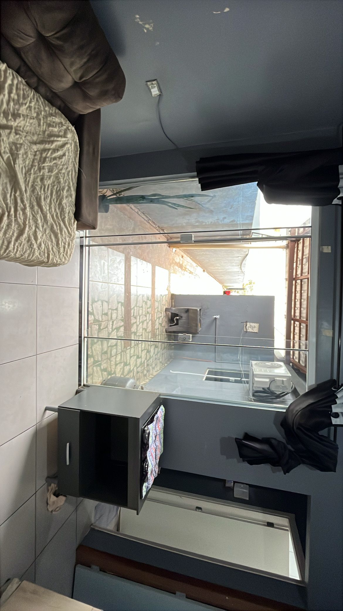 Une cuisine compacte dotée d’un four encastré, d’un petit plan de travail et d’une fenêtre donnant sur un mur en pierre.