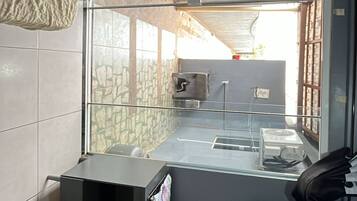 Une cuisine compacte dotée d’un four encastré, d’un petit plan de travail et d’une fenêtre donnant sur un mur en pierre.