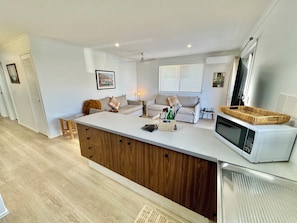 A modern kitchen with a central island, a microwave, and a dining area with a sofa. - "Palm Cove" @ Palm Beach Southern GC - Walk To Beach - Pet Friendly (Palm Beach)