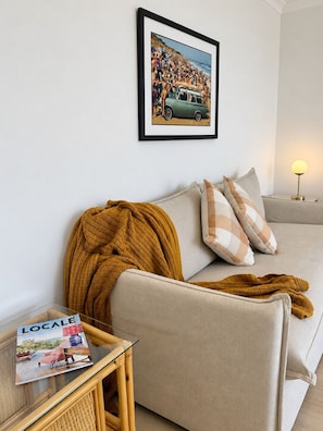 A living room with a sofa, a throw blanket, a magazine on a side table, and a framed picture on the wall. - "Palm Cove" @ Palm Beach Southern GC - Walk To Beach - Pet Friendly (Palm Beach)