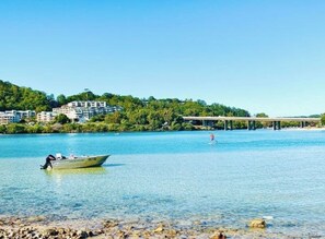 A river with a boat, a person swimming, and buildings on a hillside. - "Palm Cove" @ Palm Beach Southern GC - Walk To Beach - Pet Friendly (Palm Beach)