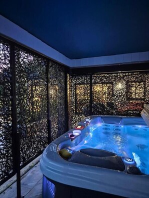 Ein Whirlpool mit modernem Design, umgeben von einem dekorativen Metallzaun.